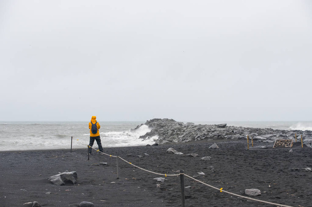 Alone man get wet on a black sand beach volcanic rocks in Vik, Iceland - Фото, изображение