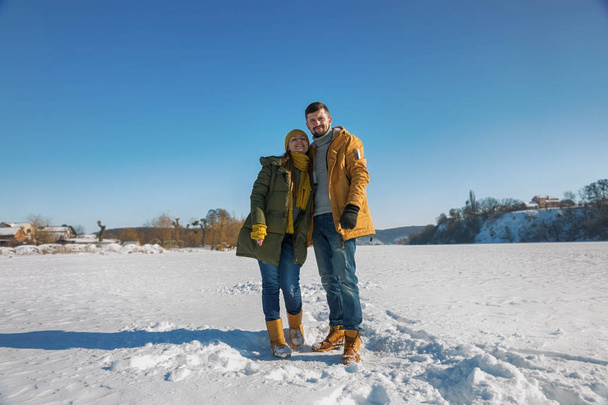 Happy young couple walking on winter sunny day. Full body, wide angle. - Foto, afbeelding
