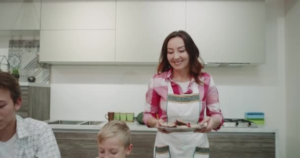 Mature woman cooking happy on the morning for her family members then brings the food on the dinner table and happy starting to take the breakfast all together. - Filmmaterial, Video