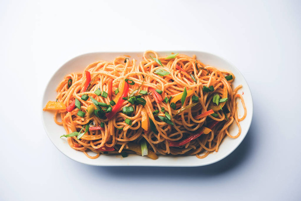Les nouilles Schezwan ou légumes Hakka Noodles ou chow mein sont des recettes indo-chinoises populaires, servies dans un bol ou une assiette avec des baguettes en bois. focus sélectif
 - Photo, image