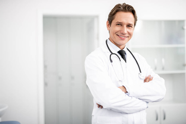 Waist up of happy doctor standing with arms crossed and smiling - Fotografie, Obrázek