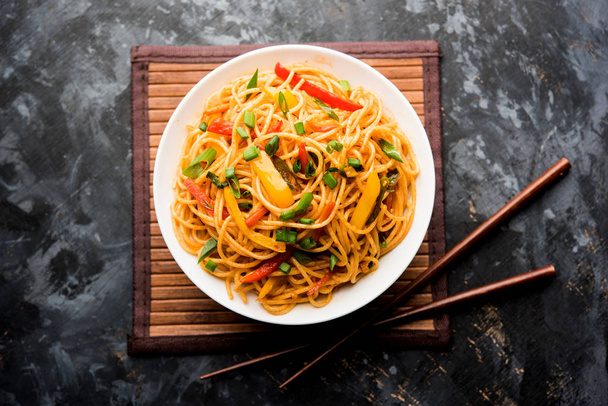 Schezwan Fideos o verduras Hakka Fideos o chow mein es una receta popular indochina, que se sirve en un tazón o plato con palillos de madera. enfoque selectivo
 - Foto, Imagen