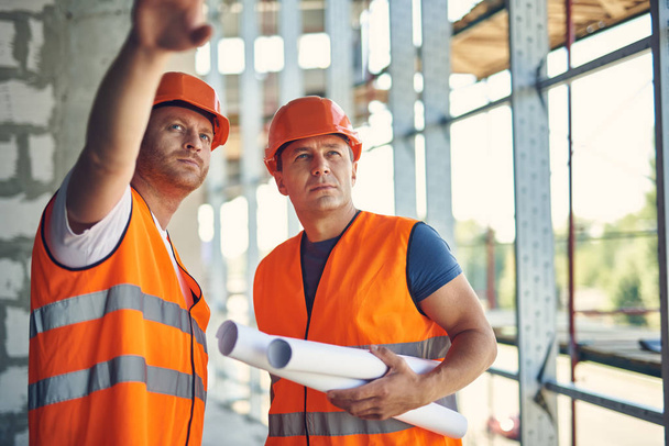 Close up of two professional builders looking into the distance - Foto, Imagen