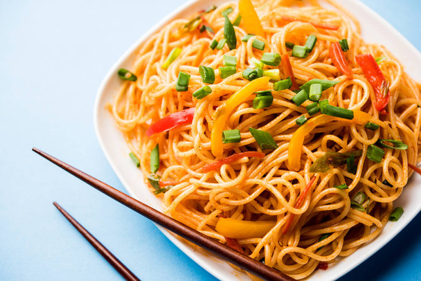 Schezwan Fideos o verduras Hakka Fideos o chow mein es una receta popular indochina, que se sirve en un tazón o plato con palillos de madera. enfoque selectivo
 - Foto, imagen