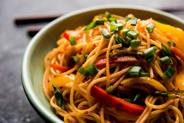 Les nouilles Schezwan ou légumes Hakka Noodles ou chow mein sont des recettes indo-chinoises populaires, servies dans un bol ou une assiette avec des baguettes en bois. focus sélectif
 - Photo, image
