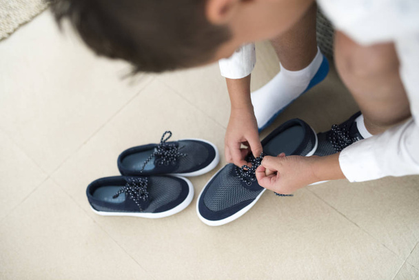 Крупним планом на дитину руки зав'язують шнурки готові для вечірки або церемонії, в двері одягаються
. - Фото, зображення