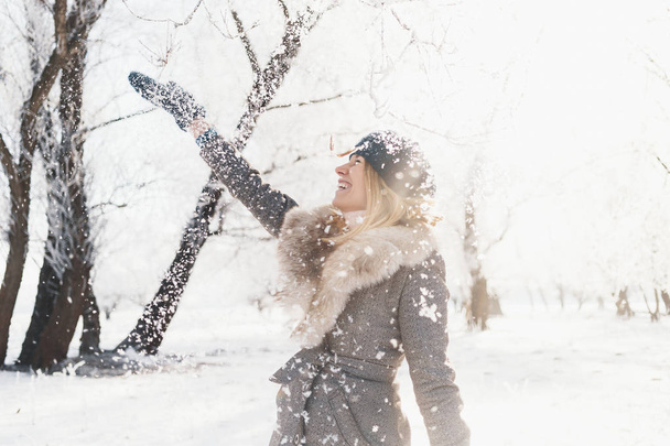 うれしそうな美少女の手を上げる、紡績、笑って、楽しんで雪と遊ぶ。冬の若い女性の肖像画。美しい若い女性が屋外に笑っています。自然を楽しむ、冬 - 写真・画像