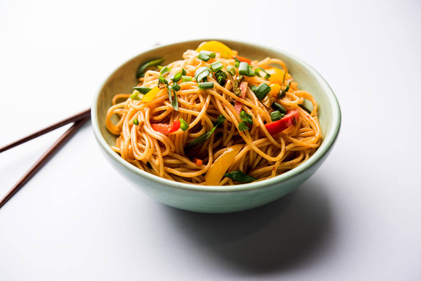 Schezwan 麺の客家麺や焼きそばの野菜は木の箸を添えてボウルやプレート人気のインド-中国語レシピです。選択と集中 - 写真・画像