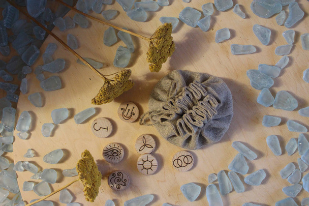 Houten handgemaakte heks runen met een linnen zakje, blauwe kristallen en gele bloemen in een rustieke stijl - Foto, afbeelding