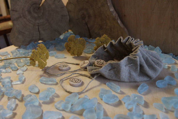 Rune streghe in legno fatte a mano con una borsa di lino, cristalli blu e fiori gialli in stile rustico
 - Foto, immagini