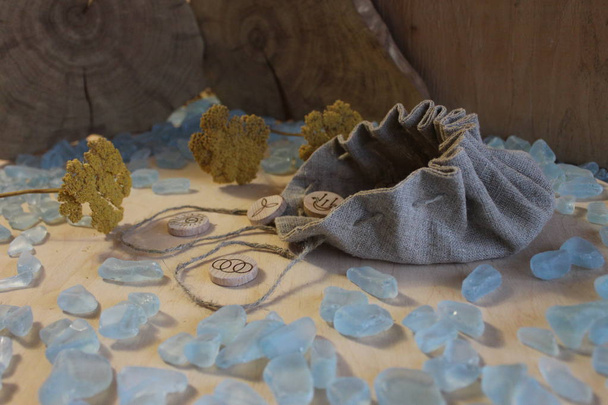 Handgemachte hölzerne Hexenrunen mit Leinentasche, blauen Kristallen und gelben Blumen im rustikalen Stil - Foto, Bild