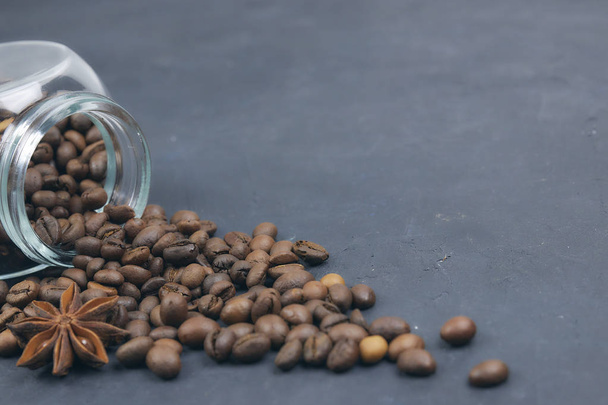 roasted coffee beans poured from a glass jar. angular placement of the coffee object. - Foto, Bild