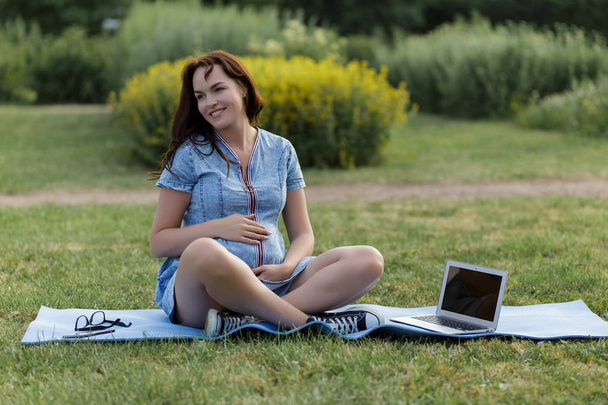 Young pregnant girl working in the park using her laptop - Foto, Bild