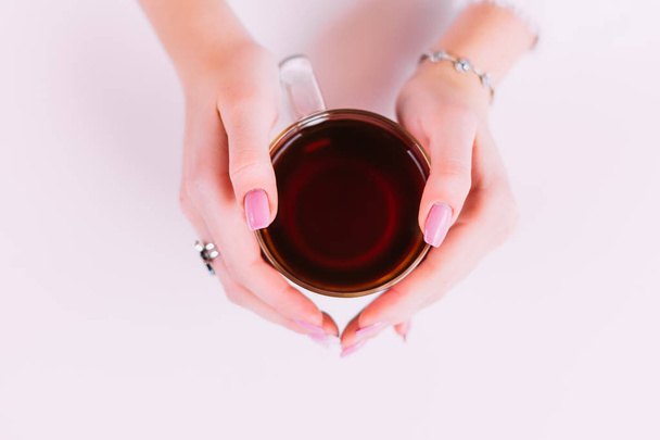 top view on the girl's hands which is around a transparent cup of tea - Photo, Image