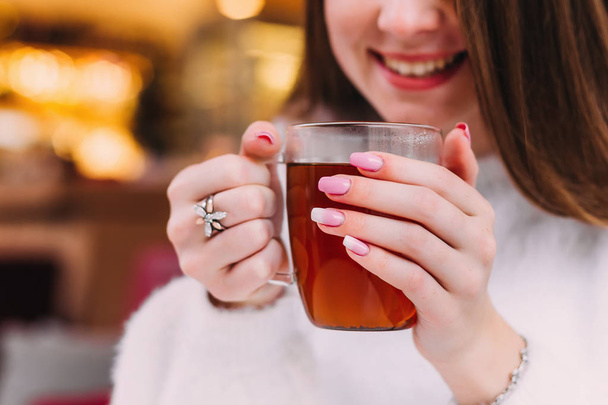 Sonriente chica que sostiene una taza de té transparente en sus manos
 - Foto, Imagen
