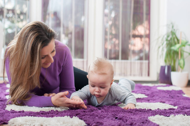 Boldog anya megállapításáról a padlón, és ő kisfiú játszik - Fotó, kép