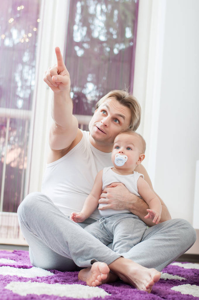 Happy father sitting on the floor and playing with his baby boy. Finger pointing. - Foto, immagini