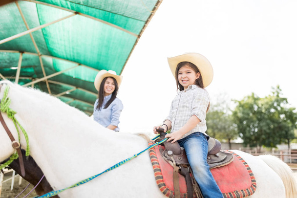 Anya és lánya, csinál egy ököl bump rövid idő lovaglás barna és a fehér ló ranch - Fotó, kép