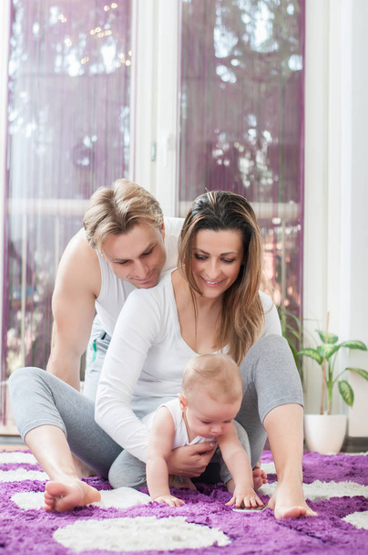Happy parents laying down on the floor and playing with their baby boy. Computer era. - Φωτογραφία, εικόνα
