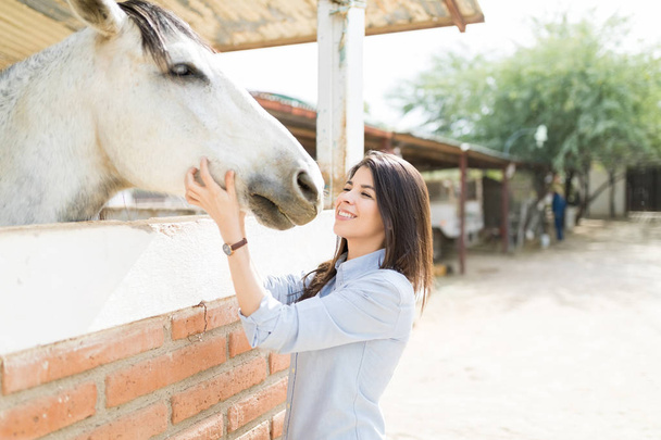 Side view of pretty adult woman about to kiss a horse at ranch - Foto, Bild
