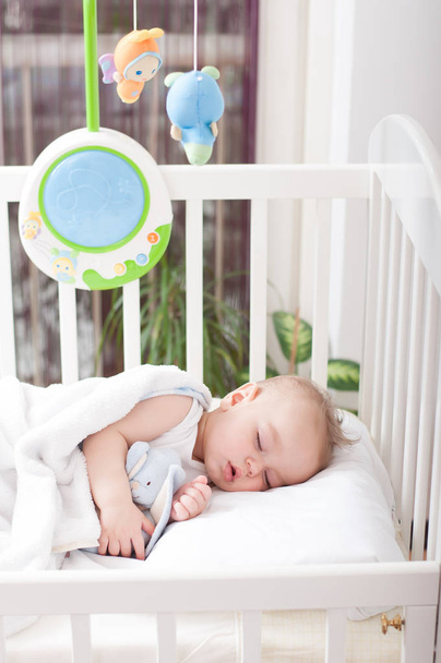 Beautiful baby boy laying down in his bed and sleeping - Photo, Image