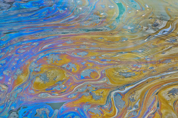 Surface water of a Texas bayou with ripples, showing a colorful oily film on top, signifying polluted oily waters. - Photo, Image