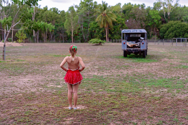 Young girl in a dance costume with hands on hips looking out towards and old car - Photo, Image