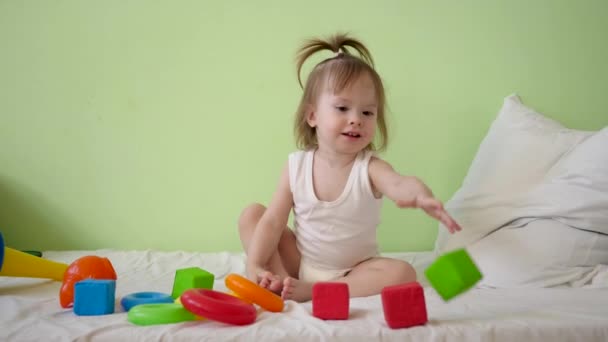 bambino gioca con cubi multicolori su un letto bianco e li getta a sua madre. Giocattoli educativi per bambini in età prescolare e d'asilo. Giocattolo per il bambino
. - Filmati, video