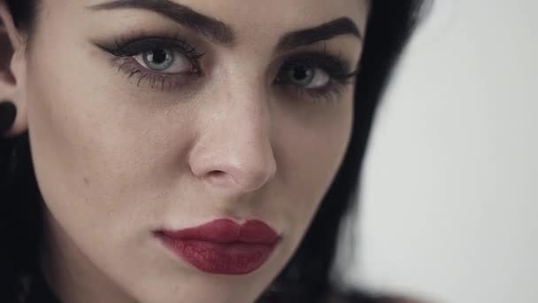 Face of cute girl with sexy lips, big blue eyes, long black hair and makeup. - Materiaali, video