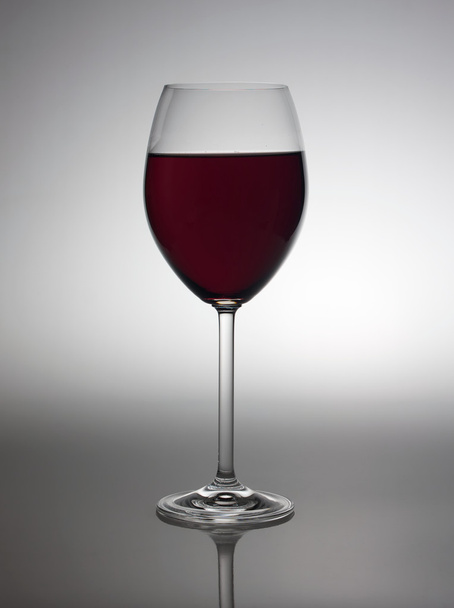 Glass with red wine in back light. - 写真・画像