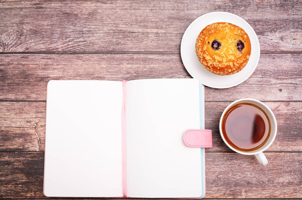 Monday Morning Concept, Hot tea and muffin cake on wooden workspace - Foto, Imagen