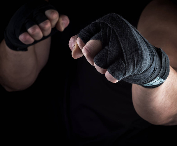 duas mãos masculinas enrolado com uma faixa têxtil preta, suporte para ataque e defesa
 - Foto, Imagem