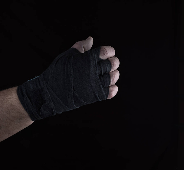męskiej prawicy jest pakowane w czarne sportowe włókienniczych bandaż na czarnym tle - Zdjęcie, obraz