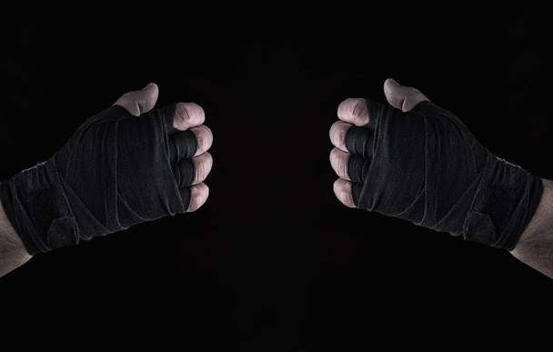 two mens hand wrapped in black sports textile bandage on a black background - Фото, зображення