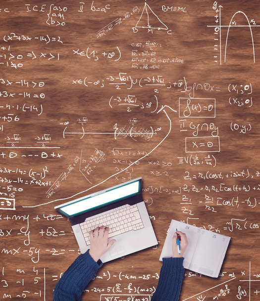 Κάτοψη των χεριών χρησιμοποιώντας φορητό υπολογιστή και να γράφει σε ένα σημειωματάριο σε ένα ξύλινο τραπέζι με μαθηματικοί τύποι. - Φωτογραφία, εικόνα