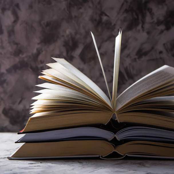 Una pila di libri aperti con pagine capovolte su sfondo grigio. Imparare la lettura e lo sviluppo personale
 - Foto, immagini
