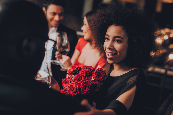 Friends in a Restaurant Enjoying Romantic Evening. Group Happy Friends Enjoying Dating in Restaurant. Double Couple Dating in Restaurant. Romantic Concept. Bouquet Red Roses. Love Concept. - Foto, afbeelding