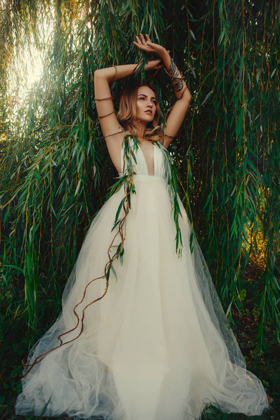 Beautiful lady is posing in a willow - Foto, Imagen