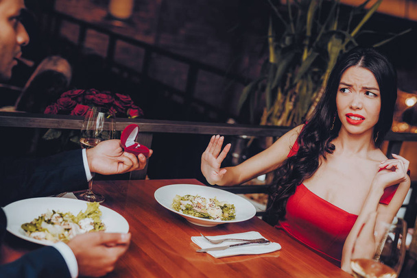 Man Proposing Engagement Ring and Getting Denied. Romantic Hispanic Couple in Love Dating. Cutel Man and Girl in a Restaurant. Romantic Concept. Negative Reaction to Proposing. Disappointment. - 写真・画像