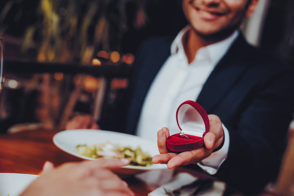 Close Up Handsome Man Proposing to Girlfriend. Romantic Couple in Love Dating. Cutel Man and Girl in a Restaurant. Romantic Concept. Surprised Attractive Woman Getting a Marriage Proposal. - Фото, изображение