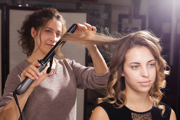 hairdresser making a hairdo with curls to a model - Фото, зображення