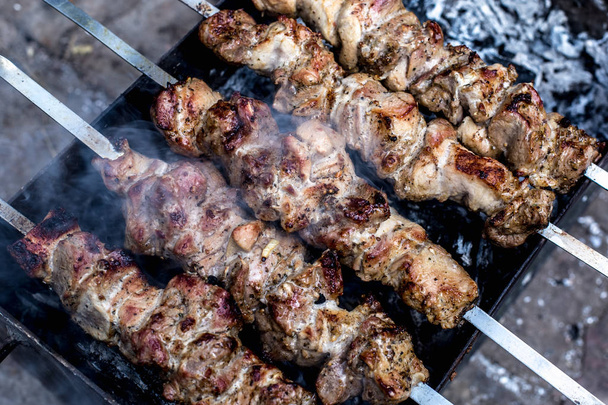 Grilled kebab cooking on metal skewers (grill). Roasted meat cooked at barbecue with smoke. Close up BBQ fresh pork meat chop slices. Traditional eastern dish, shish kebab. - Photo, Image