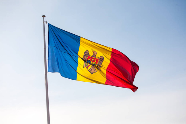 Bandeira da Moldávia no mastro de bandeira contra o céu azul
 - Foto, Imagem
