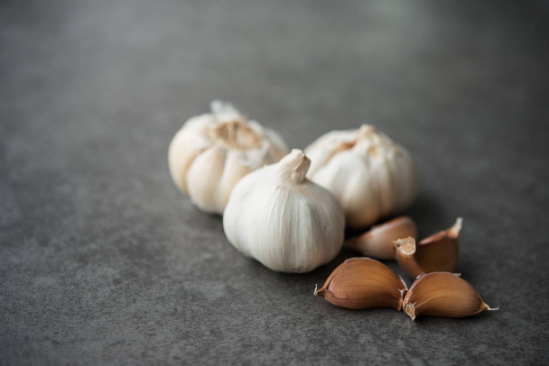 Garlic cloves and bulb with copy space on dark background. - Zdjęcie, obraz