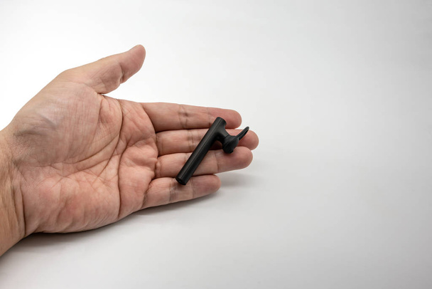 Mão segurando o receptor bluetooth mãos livres preto, isolado em um fundo branco
 - Foto, Imagem
