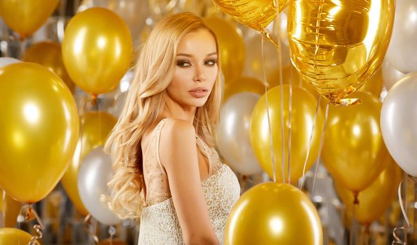 portrait of blond young woman between golden balloons and ribbons with a sweet smile - Photo, image