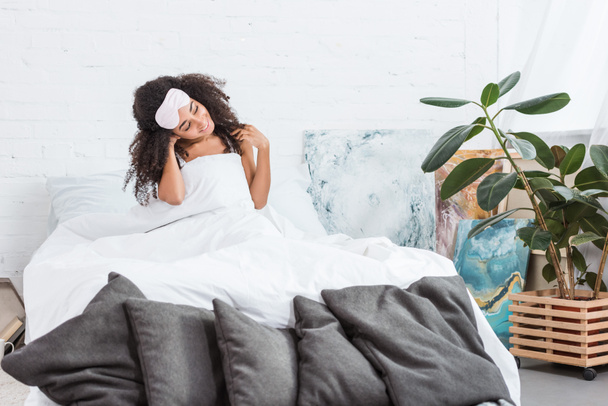 boldog fiatal afrikai-amerikai nő, bekötött szemmel a homlokán ült az ágyban reggel időben otthon - Fotó, kép