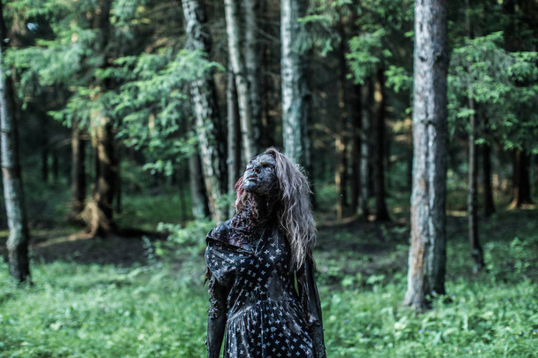Scary zombie woman posing at forest path - Photo, image