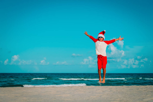 happy little boy enjoy celebrating christmas on tropical beach - 写真・画像
