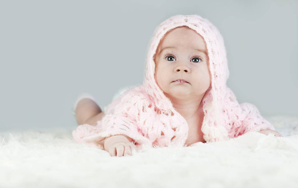 Retrato de un hermoso bebé brillante arrastrándose en una capucha en la cama en su habitación
 - Foto, Imagen